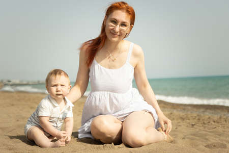 Happy mom with her little baby son on the sand beachの写真素材