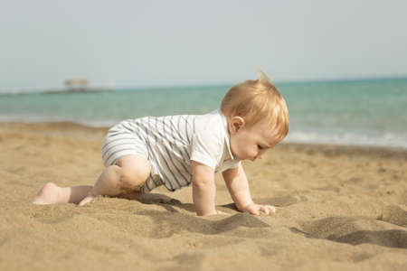 A baby boy crawling on a sand on the seasideの写真素材
