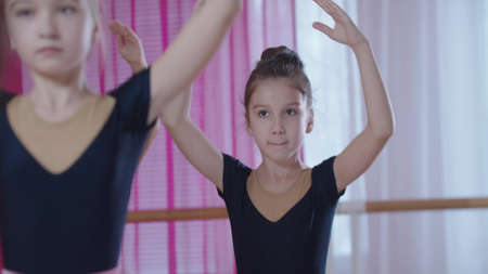 Ballet training - four girls in beautiful dresses training ballet dance in the studio