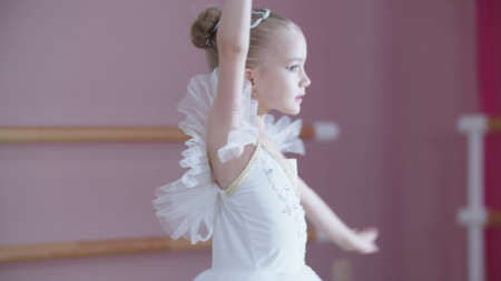 Ballet training - a little girl in white dress spinning on the spotの写真素材