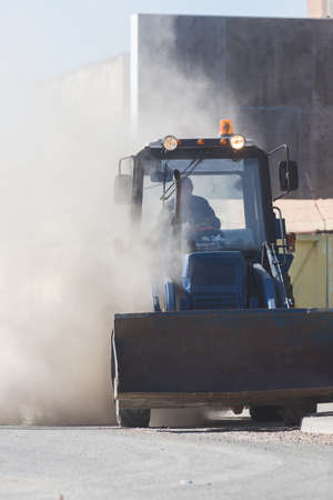A little excavator with a bucket in the dustの写真素材