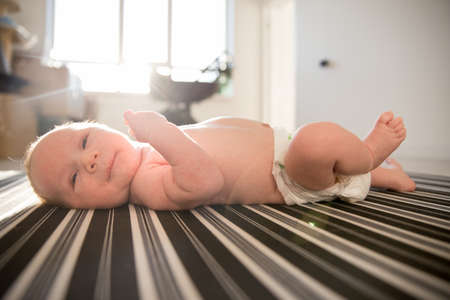 A newborn baby in a diaper lying on a made-up bed