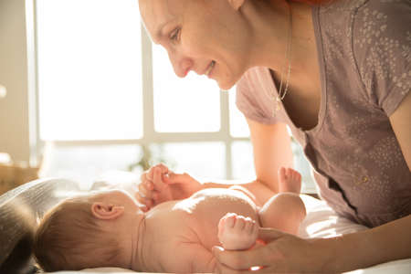 Smiling caring mother playing with her little babyの写真素材