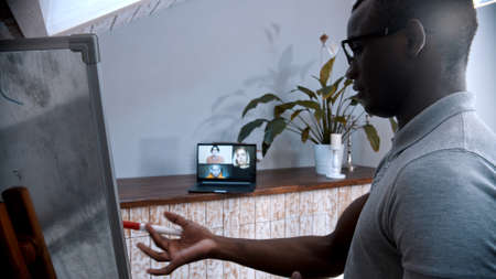 An online lesson - an african-american man teacher standing by the board and explains the material...