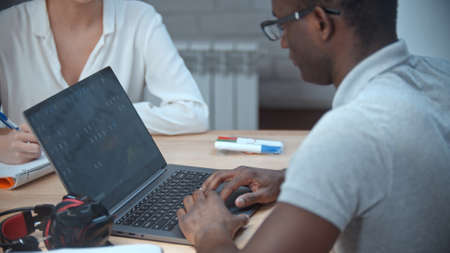 African-american man and caucasian woman having a business meeting in the office - the man working by the laptopの写真素材