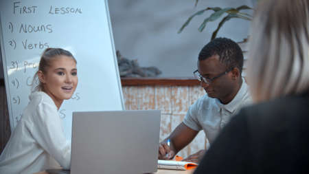 A white woman and black man having an english lesson - the teacher watching themの写真素材
