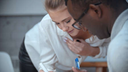 A woman bends down to her black male colleague