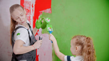 Mom and doughter play with paint fun while painting walls in new apartmentsの写真素材