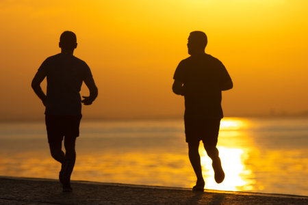 The two men running at the sunrise on river coastの写真素材