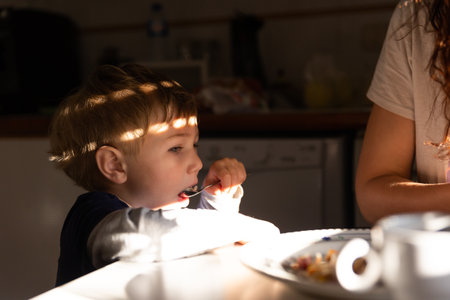 A Little Boy Eats at a Tableの写真素材