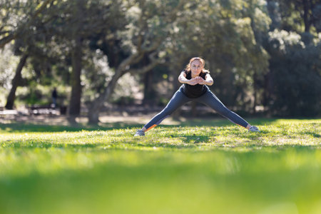 Sports woman stretching her legs and bending down in natureの写真素材