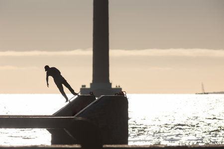 Skateboarder trains on the waterfront on the ramp at early sunsetの写真素材