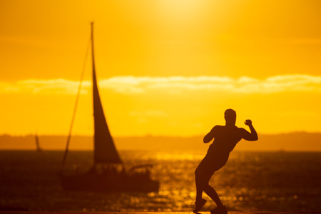 An inspired man dancing on the waterfront at sunsetの写真素材