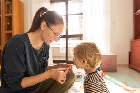 Mom feeds her son freshly made cookies in the playroomの写真素材