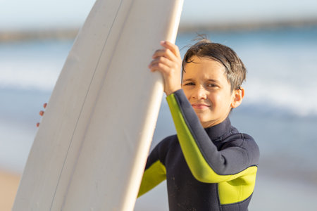 Cute little boy in a wetsuit holding a surfboardの写真素材