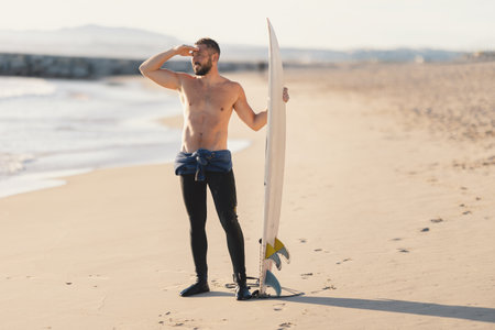 An athletic man surfer with naked torso looking in the distanceの写真素材