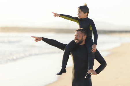 Little son on the shoulders of his father pointing to the seaの写真素材