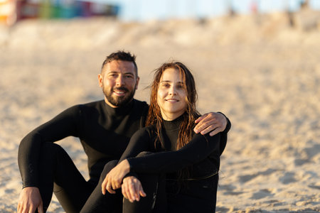 A couple of man and woman surfers sitting on the seashoreの写真素材