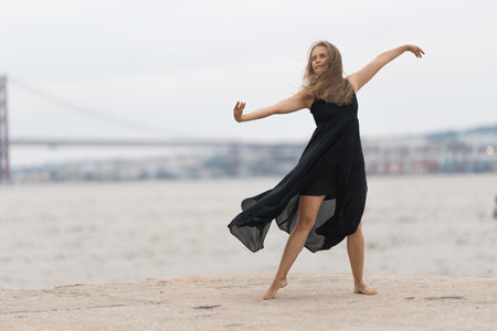 An adult woman in black dress dancing on the pierの写真素材