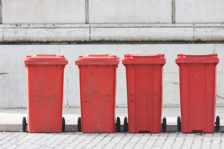 Red trash cans stand in a row on the streetの写真素材