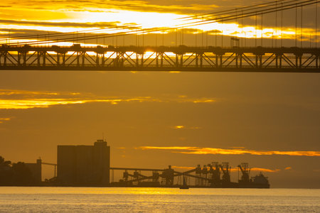Loading industrial cranes in the distance in a bright yellow sunset - industrial cityscape