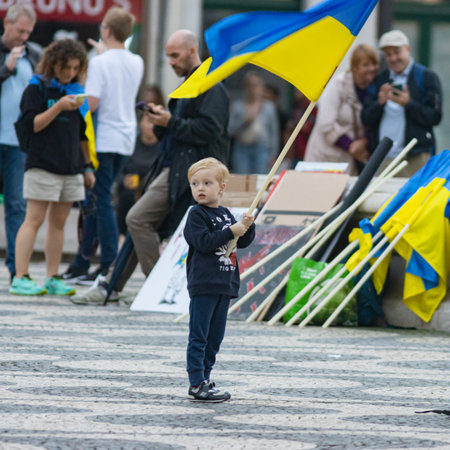 10-29-2022 LISBON, PORTUGAL: Ukrainian protest in Lisbon - a little boy holds a Ukrainian flag in the square during a protestのeditorial素材
