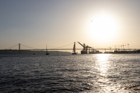 Bridge, boats and industrial cranes - sunset over the riverの写真素材