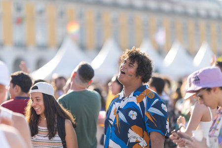Lisbon, Portugal - 24 june 2023 - Terreiro do Paco Praca do Comercio: a guy in the crowd with an LGBT rainbow flag painted on his cheek sings along to the musicのeditorial素材
