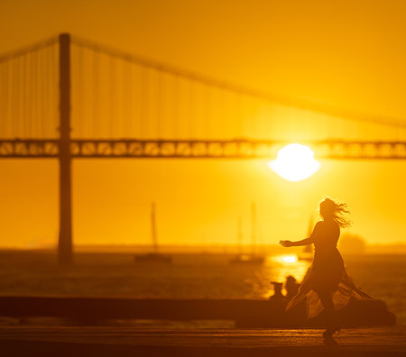 Dancers silhouette with sun and bridge.