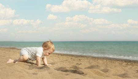 A baby boy crawling on a sand on the seaside