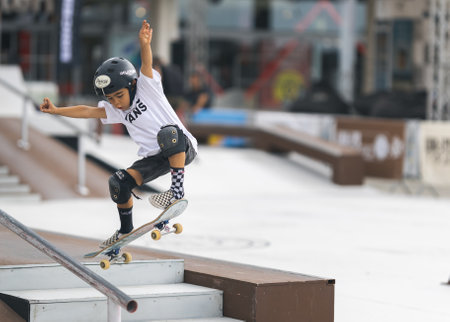 24 september 2023, Almada, Portugal - boys in blue short riding and jumping on skateboard in center of cityのeditorial素材