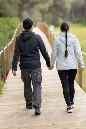 A man and woman are walking on a wooden bridge