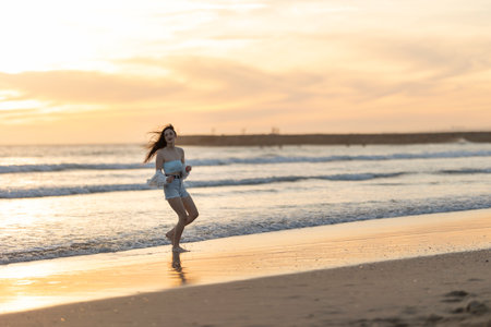A woman is running on the beach at sunsetの写真素材