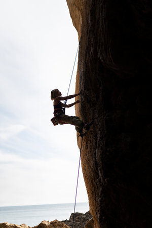 A woman is climbing a rock wall with a rope