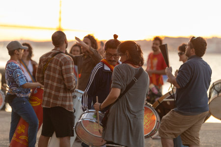 Almada, Portugal - 9 may 2024, - a group of people are playing drums on a pier in front of 25 de...
