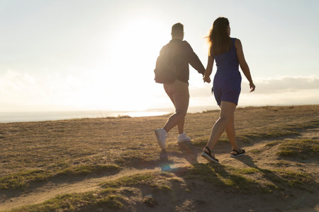 Loving couple walking on dirt path at sunset near oceanの写真素材