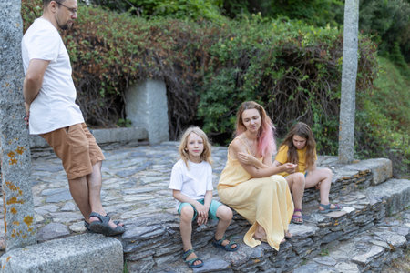 Family relaxing on stone steps in parkの写真素材