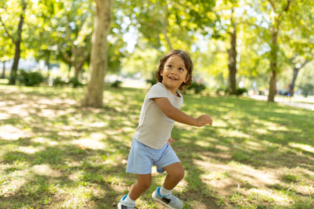 Carefree child running through sunny park on summer dayの写真素材