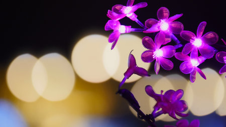 Purple flower led lights shining on dark background with yellow bokehの写真素材