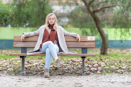 Young woman relaxing on park bench in autumnの写真素材