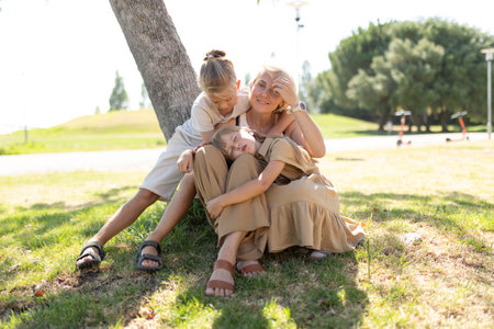 Family bonding under a tree in a sunny parkの写真素材