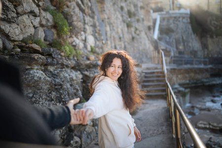 Tourist holding hand while walking near cliff face at sunset