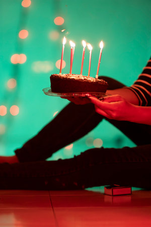 Woman holding birthday cake with lit candles in atmospheric lighting