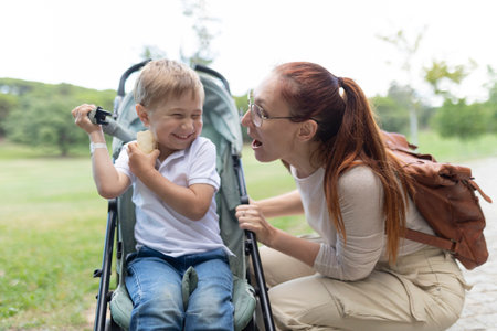 Happy family having fun outdoors while mother pushing son in stroller in a parkの写真素材