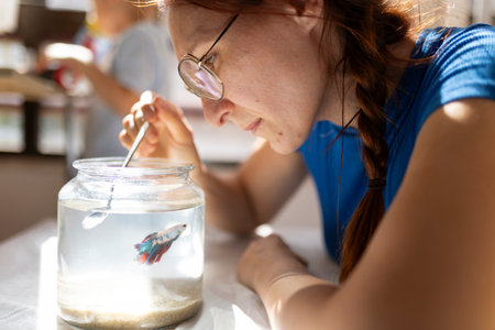 Woman cleaning fishbowl with small fish inside