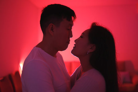 Young couple sharing intimate moment in red-lit room