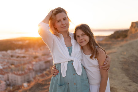 Mother and daughter embracing at sunset with city view in backgroundの写真素材