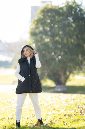 Fashion model posing in a park during a sunny autumn dayの写真素材