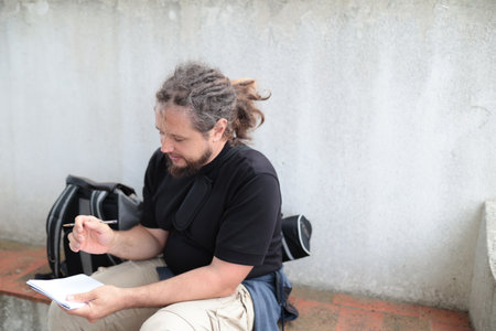 Journalist writing notes outdoors, taking a break from reportingの写真素材