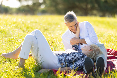 Happy senior couple relaxing in a meadow on a sunny dayの写真素材